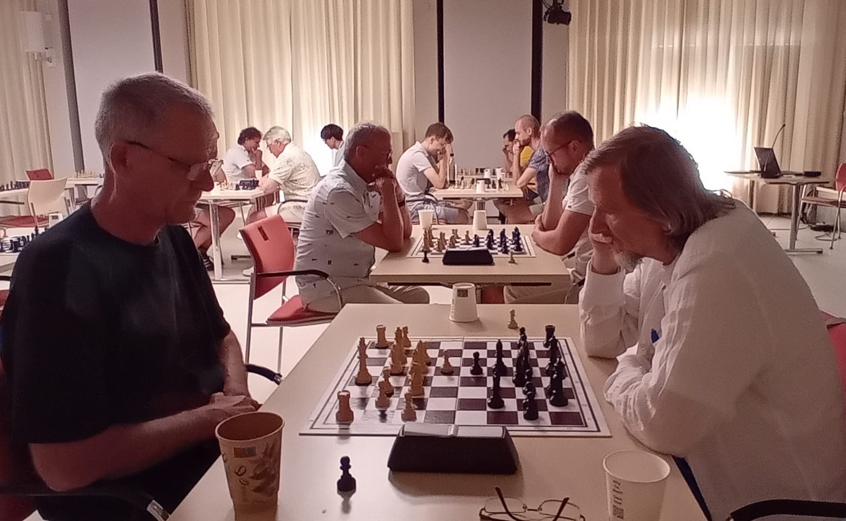 Schachbrett im Vordergrund mit Spielern im Hintergrund